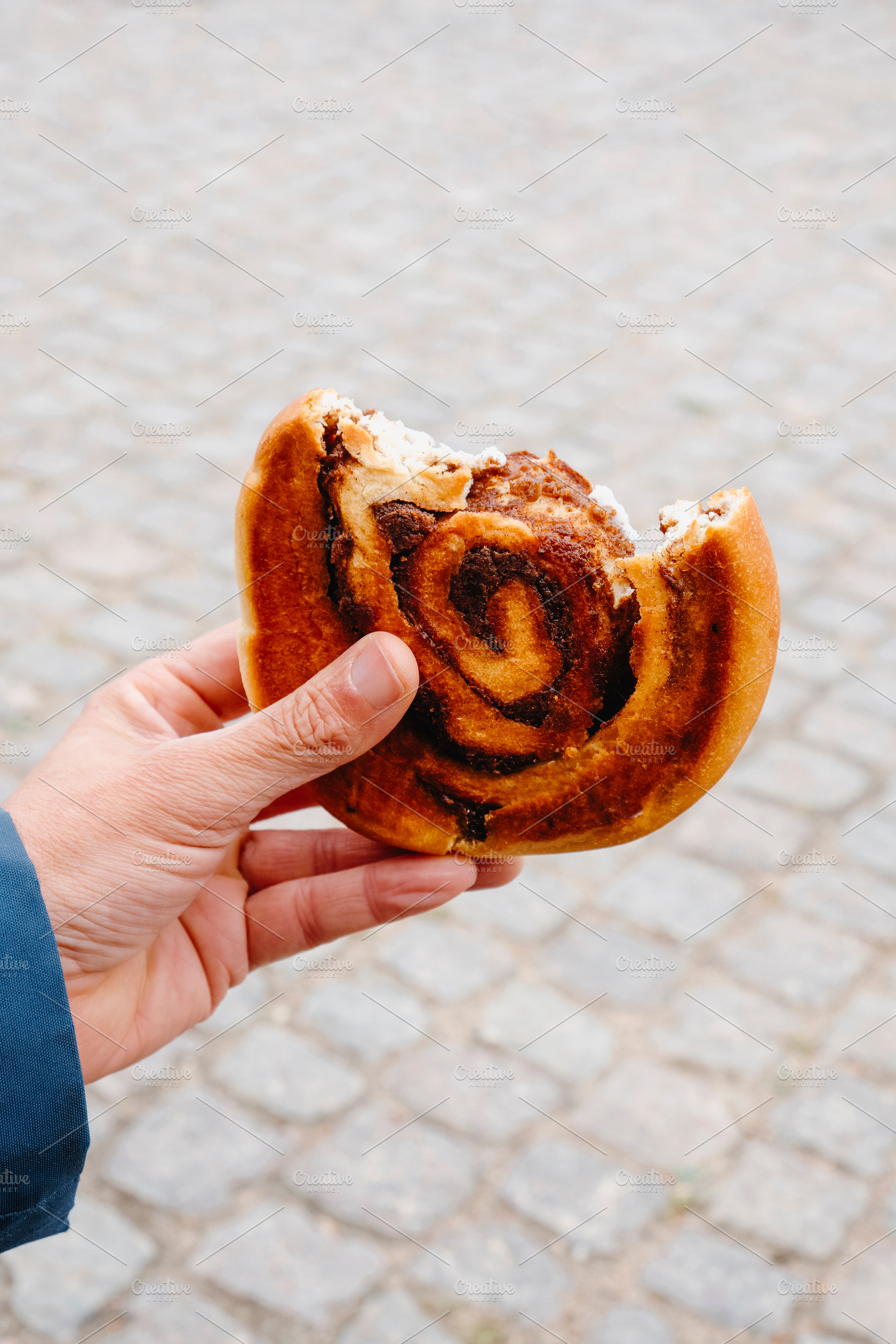 a man holding a bitten danish kanelsnegl, a Photo by Nito