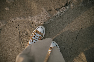 Feet in sneakers near water