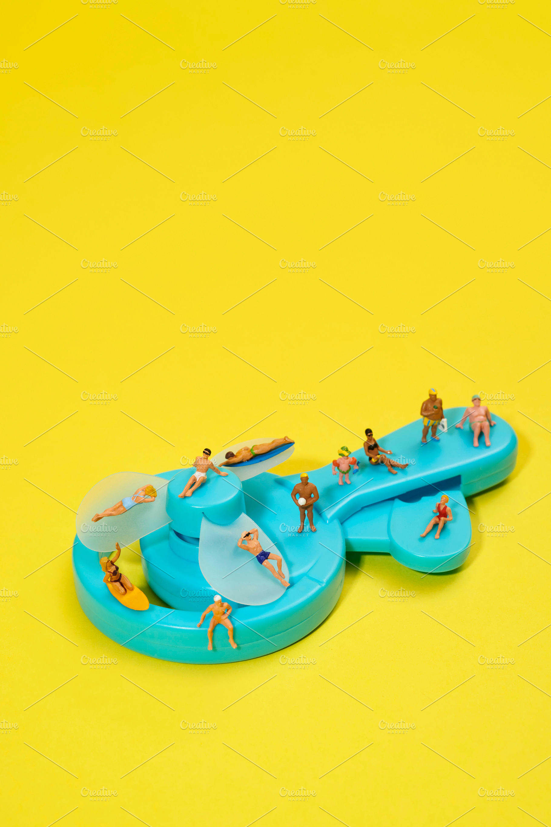 miniature people in swimsuits on a blue fan, a Photo by Nito