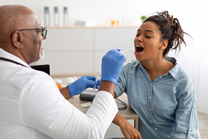 Doctor taking PCR test sample from potentially infected black woman, a Photo by Prostock-Studio