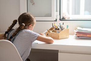 Young girl studying and writing homework at desk at home, a Photo by etorres69