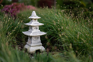 Serene stone pagoda sculpture amidst a lush garden landscape, a Photo by AS photostudio