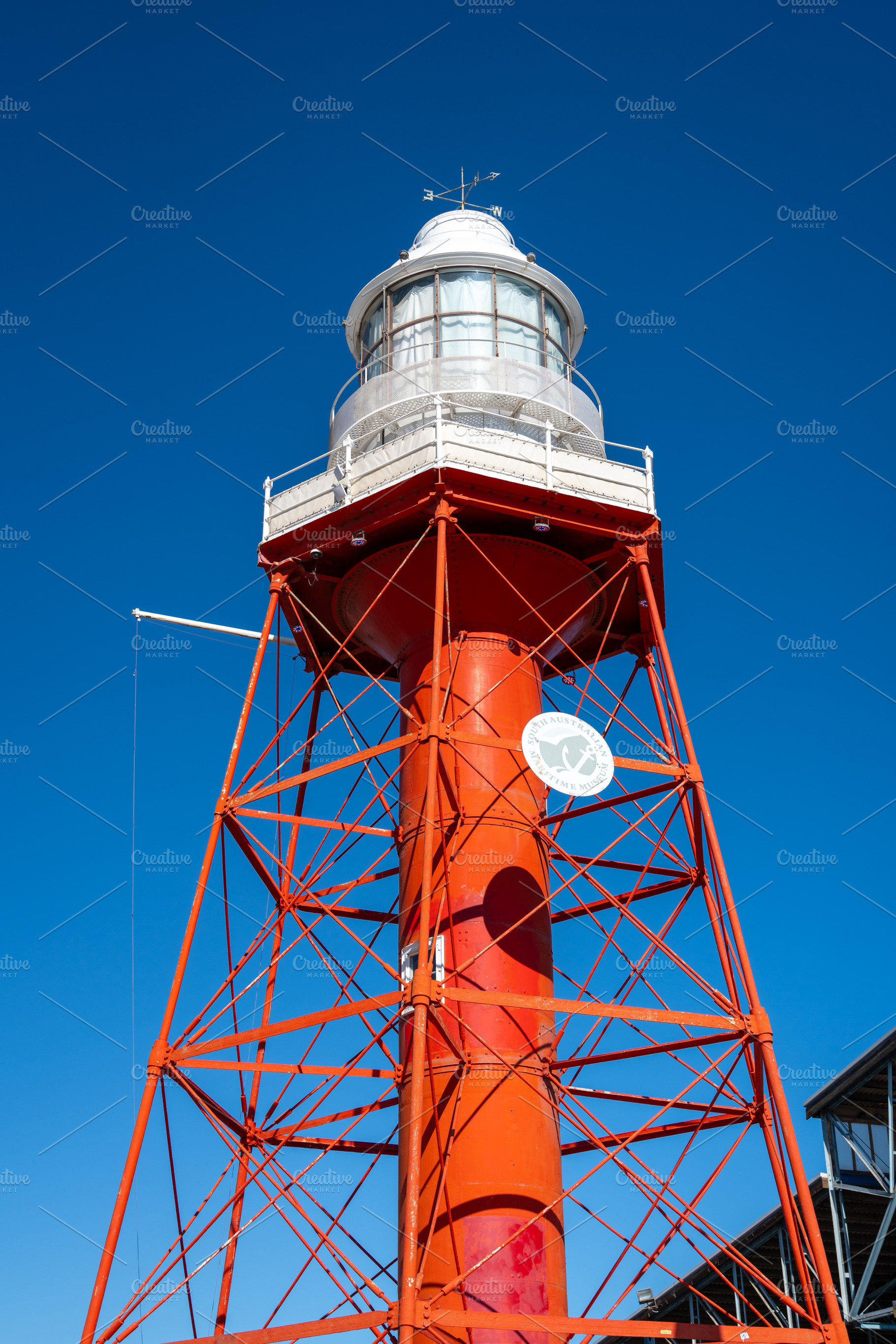 Red lighthouse with metal structure under blue sky in Adelaide,, an Architecture Photo by GoodGoods