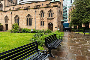 Quiet churchyard with wet benches and stone path in Liverpool, U