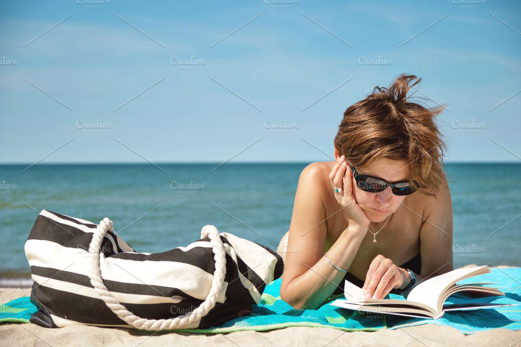 Mature woman reading on the beach, a Person Photo by BOOCYS