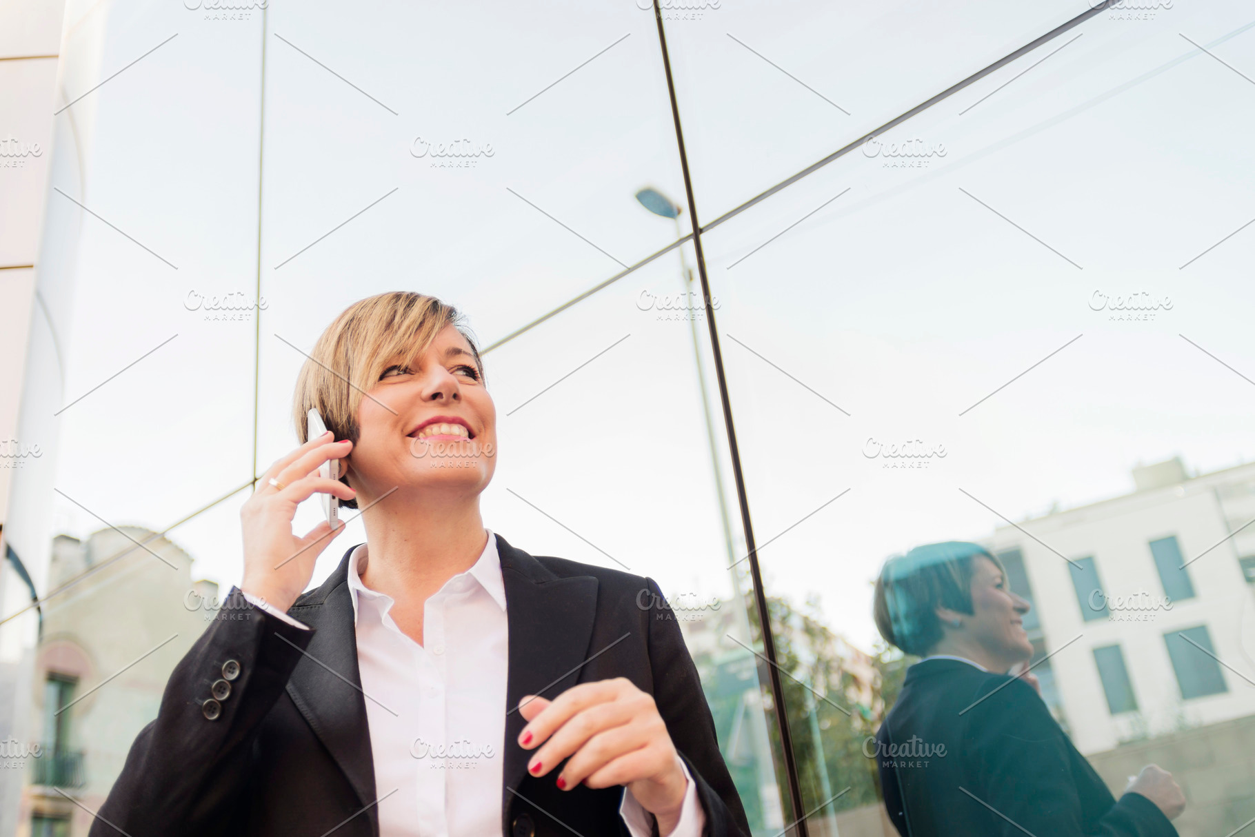 Businesswoman on phone by modern glass building, a Photo by RF Images