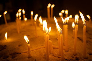 Burning candles with warm flames placed in a bed of sand, an Abstract Photo by GoodGoods