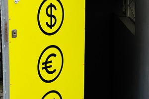 Yellow exchange sign with currency symbols displayed on a doorway, a Photo by AS photostudio