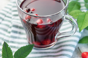 Rosehip tea brewing in glass cup with fresh rose hips and leaves, a Food & Drink Photo by Olena Rudo