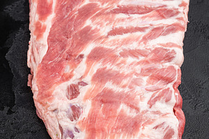 Raw pork spareribs slab with bone and butcher knife flat lay on