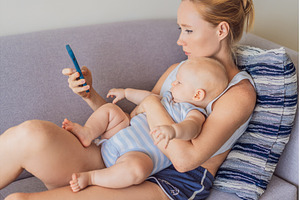 Baby sitting on mother lap while she, a Technology Photo by Elizaveta Galitskaya
