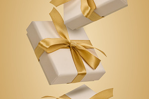Floating beige gift boxes with gold satin ribbons and bows., a Holiday Photo by ndanko