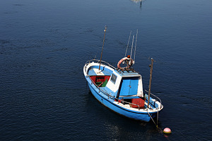 Blue fishing boat anchored in calm w, a Transportation Photo by Perpis