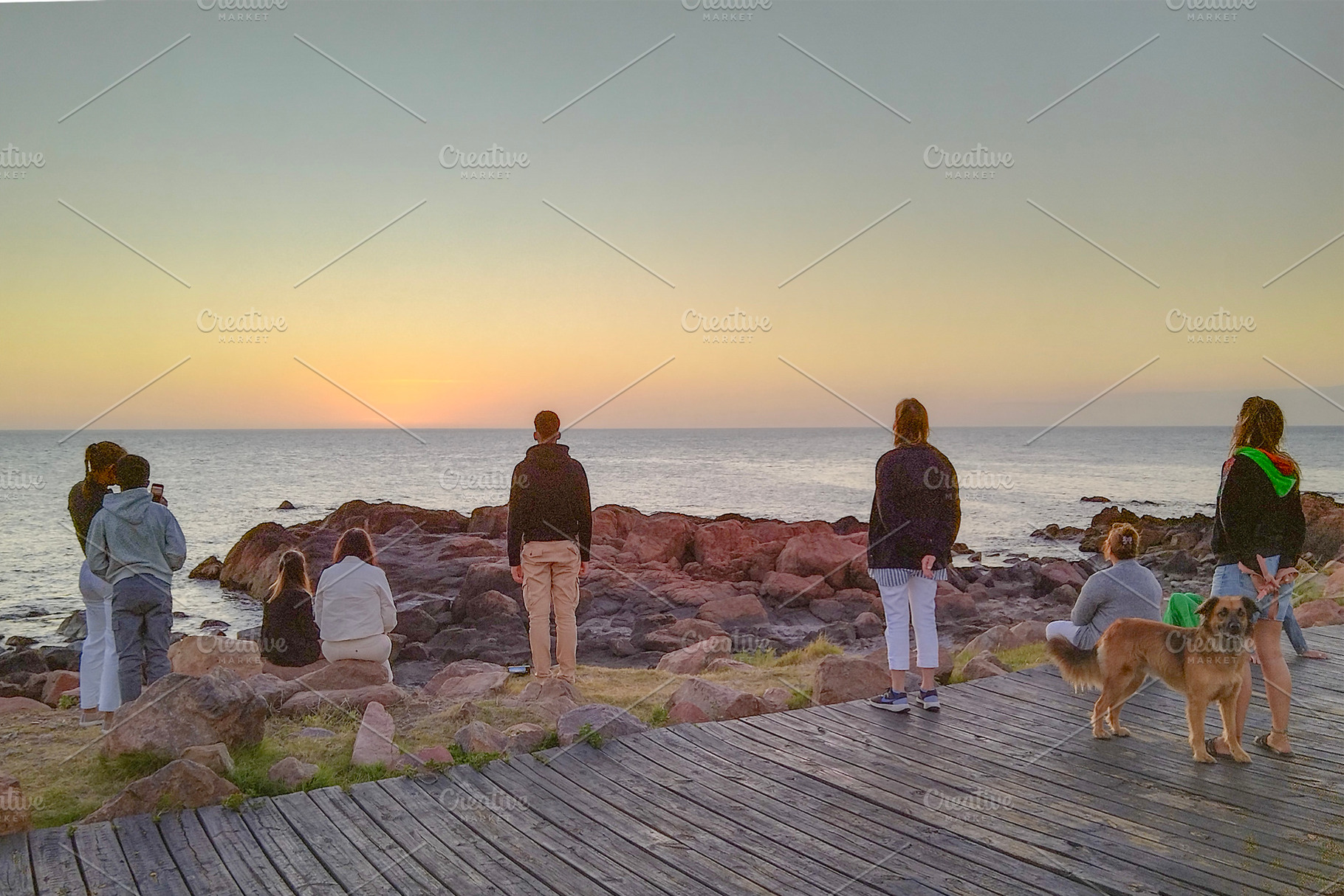 Group meditating and watching ocean at sunset, a Person Photo by DanFLCreativo