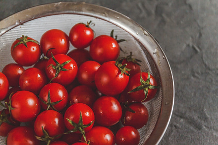 raw whole washed cherry tomatoes in a colander on a dark concret, a Food & Drink Photo by TanaCh