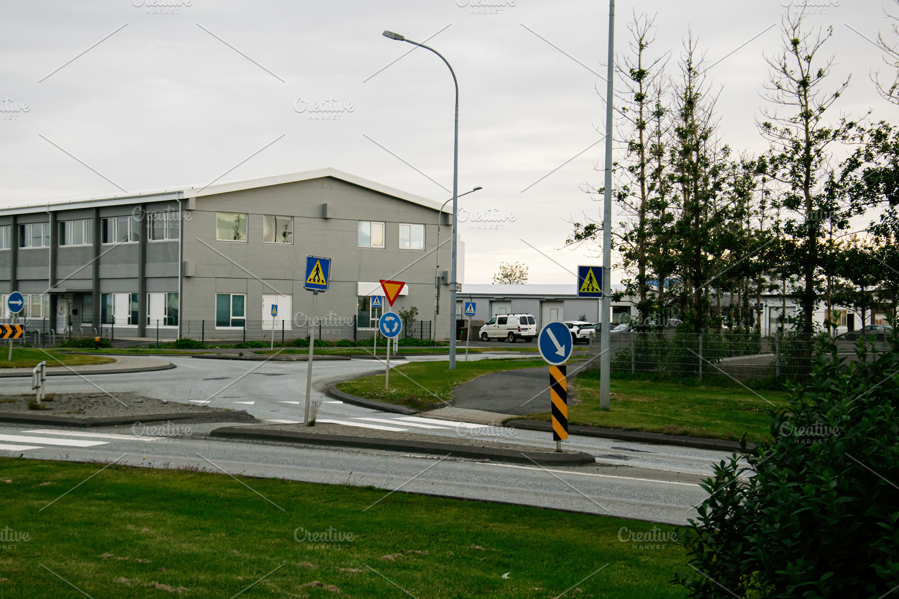 Roundabout with road signs near industrial buildings on a cloudy day in Akranes, a Photo by AS photostudio