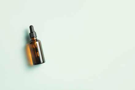 Amber glass dropper bottle with black lid on blue background. Sk, a Beauty & Fashion Photo by Natalia Klenova's Shop