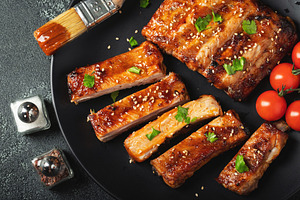 Hot grilled spare ribs from a summer BBQ served on a plate with sauce. Top view, a Food & Drink Photo by Budarinphoto