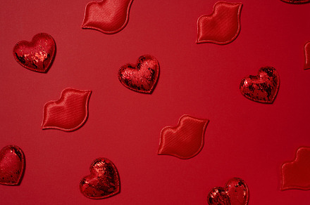 Red decorative hearts and lips randomly placed on a bright red b