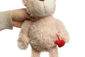 Human hand holding pink teddy bear with small red heart, isolate, an Abstract Photo by ndanko