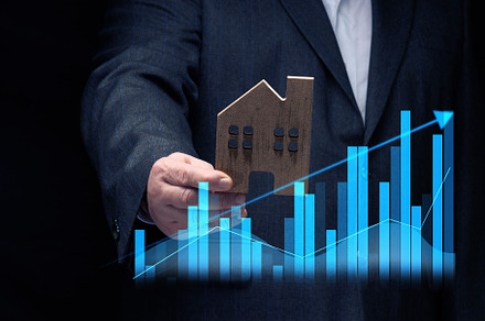 hand holds a wooden model of a house on a dark background. Real, a Business Photo by ndanko