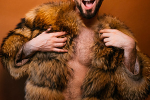 Gay man expressing joy and self-confidence in fur coat, a Photo by karrastock