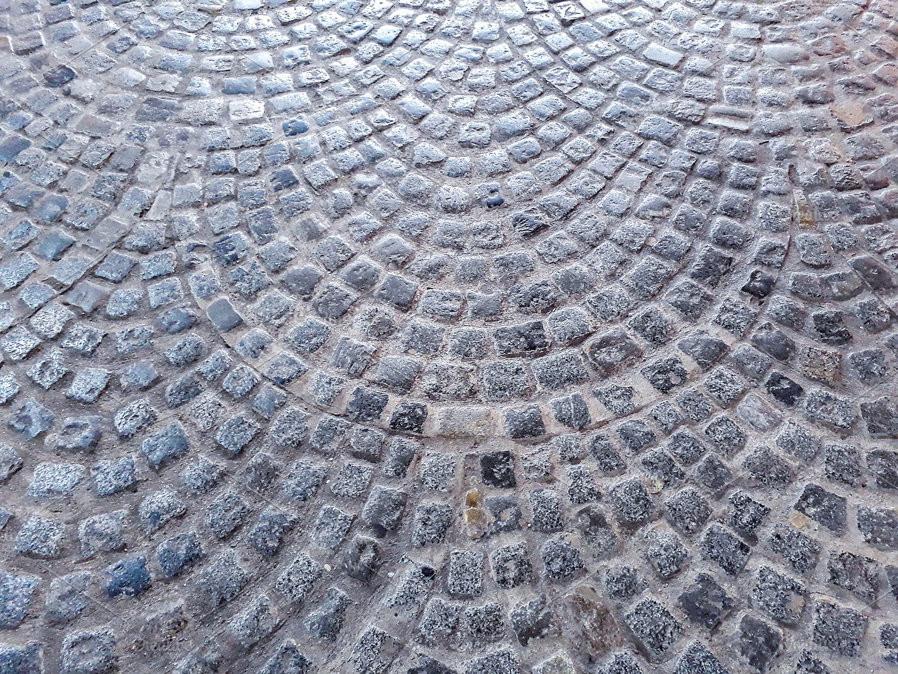 Circular cobblestone pavement with wet texture, a Background Photo by DanFLCreativo