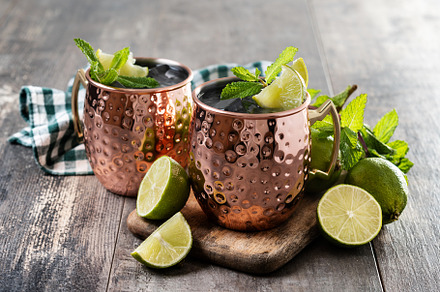 Moscow mule cocktail served with ice and lime slice on wooden table, a Food & Drink Photo by etorres69