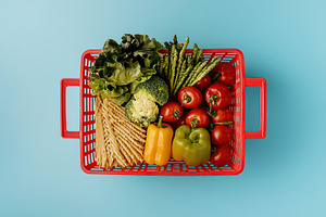 Top view of shopping basket full of different grocery products on blue backgrou, a Food & Drink Photo by AlyaAnd