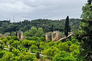 Lush greenery surrounding Tomar castle with cloudy skies in the background, a Photo by AS photostudio