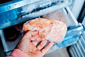 a man takes frozen chicken from the freezer, a Photo by Nito