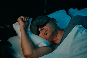 a man resting with a sleep mask in a bedroom, a Photo by Nito