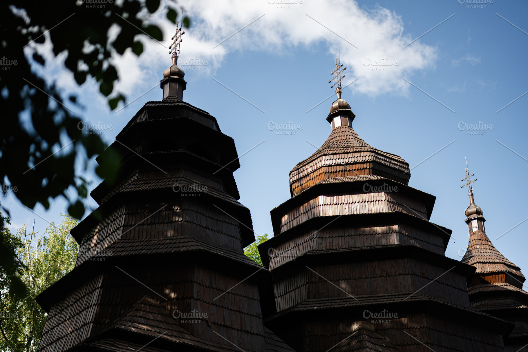 Traditional wooden church structure under a blue sky with scattered clouds, a Photo by AS photostudio