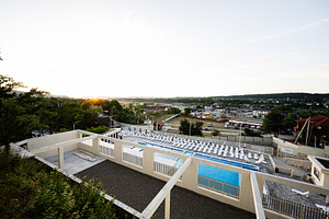 Spacious outdoor pool area overlooking a scenic village at sunset, a Photo by AS photostudio