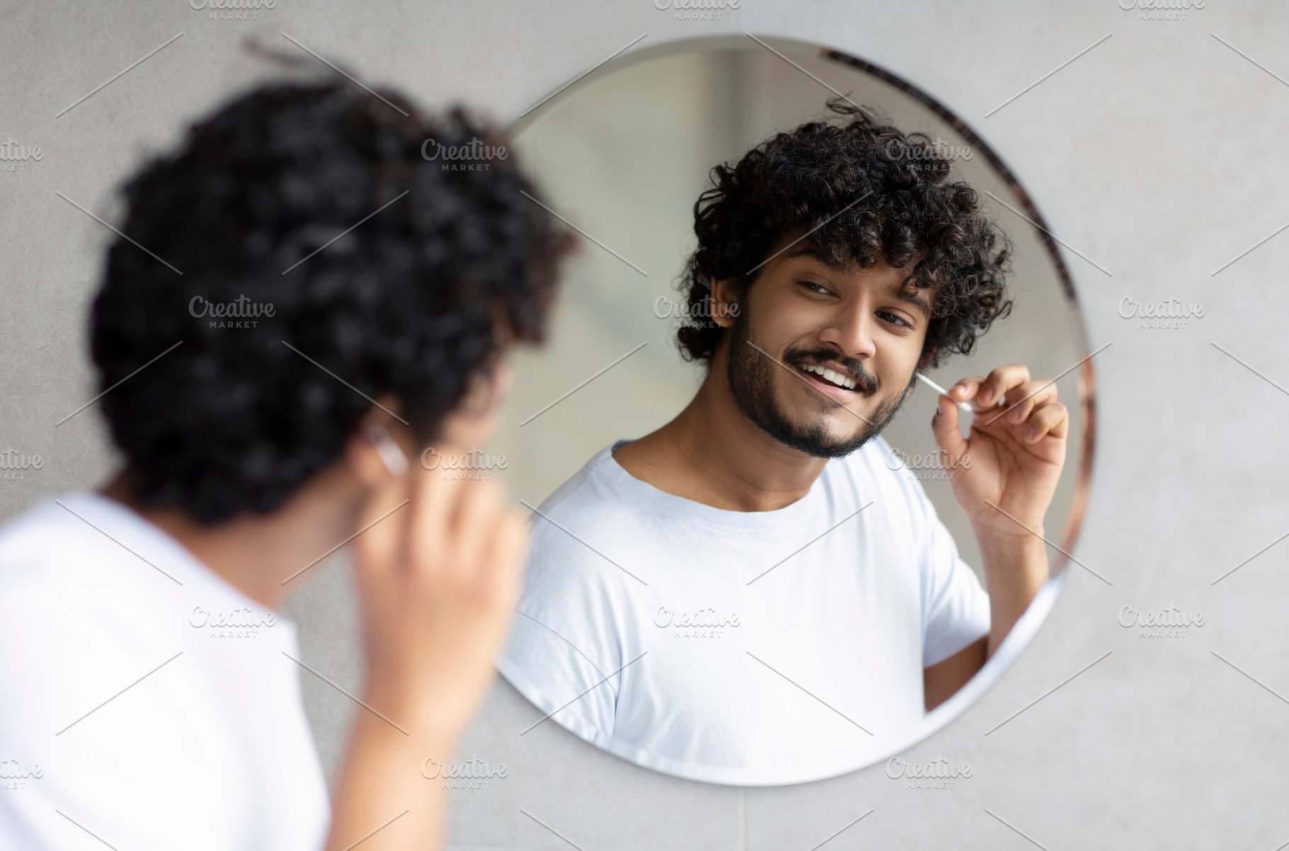 Daily hygiene routine. Indian man cleaning ears using cotton swab while doing m, a Person Photo by Prostock-Studio