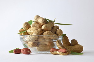 Glass bowl with shelled peanuts showing on white background, a Food & Drink Photo by Davizro's Market