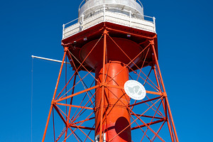 Red lighthouse with metal structure under blue sky in Adelaide,, an Architecture Photo by GoodGoods