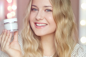 Blonde woman smiling, holding white beauty product jar, presenti, a Person Photo by Anneleven