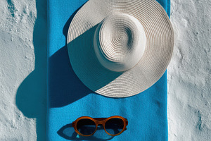 Blue beach towel with sunglasses, a Photo by Virgo Studio