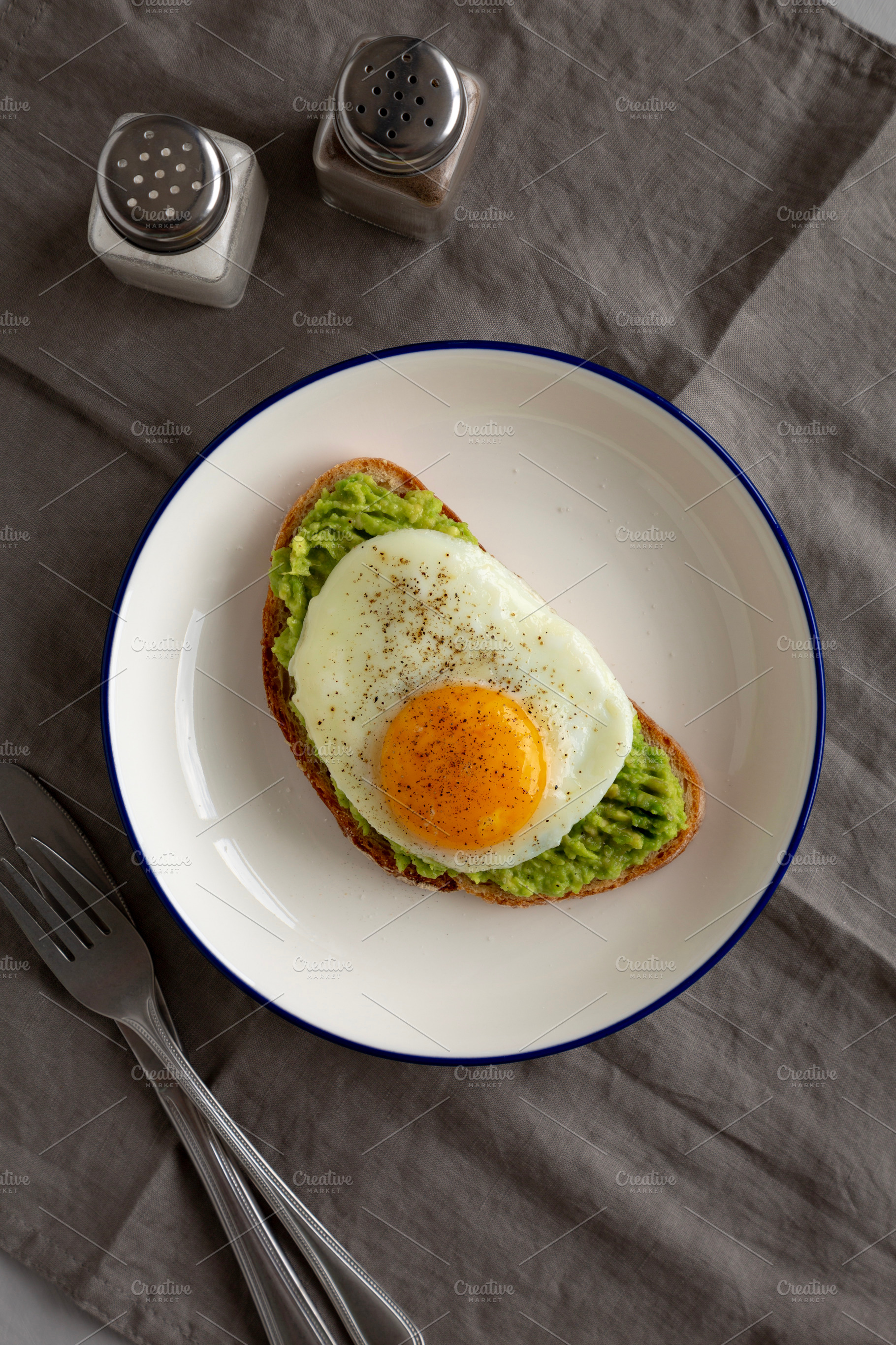 Homemade Avocado Toast with Egg on a Plate, top view., a Food & Drink Photo by LiudmylaChuhunova