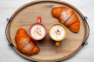 Delicious breakfast with two mugs of cappuccino and two croissants on wooden tr, a Food & Drink Photo by Antonio Gravante Market