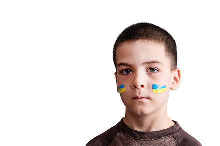 Child against war. Upset Ukrainian boy with bue yellow flag on his face
