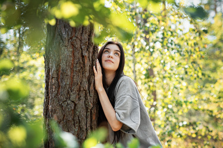 Young woman enjoying a peaceful moment by a tree in a lush green, a Person Photo by Olena Rudo