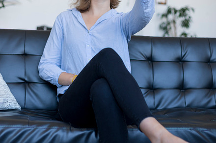 Young smiling woman sitting on leather sofa with headphones taking a selfie, a Person Photo by RF Images