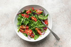 Fresh green salad with tomatoes and red onion, a Food & Drink Photo by Olena Rudo