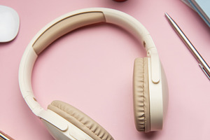 Wireless headphones laying on pink desk with keyboard, mouse, an, a Business Photo by Olena Rudo