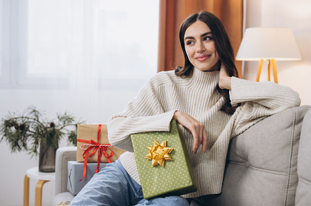 Beautiful happy woman unwrapping New Year or Christmas presents