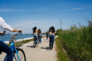 Tourist women riding bike in Pellestrina Island, an Architecture Photo by Bepslabor