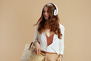 smiling elegant woman listening to music on beige, a Person Photo by Alliance Images