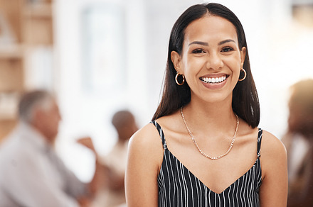 Happy, smiling and a portrait of woman at work and coworkers in blurred background. Success, pride and confidence, businesswoman with smile in office. Leadership, management and empowerment of women., a Photo by Peopleimages.com